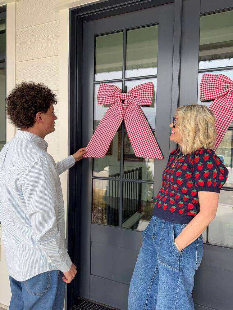 jake and jeneil look at a red gingham bow on door
