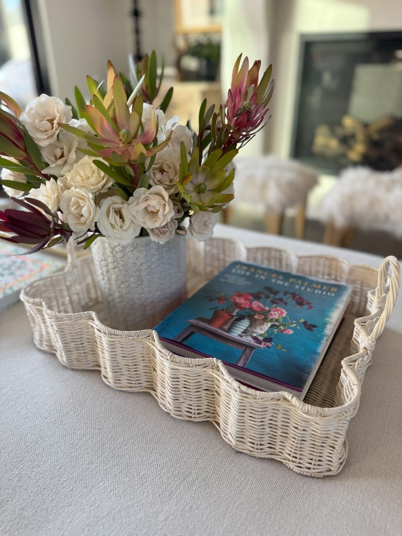 White scalloped wicker basket with blue book and jar of plants