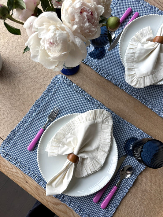 Blue Belle Ruffled Placemats with White Ruffled Napkins on top and pink handled silverware