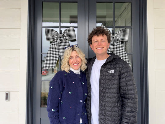 Jake and Jeneil stand in front of their porch doors, featuring two black gingham door bows