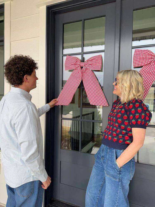 jake and jeneil look at a red gingham bow on door