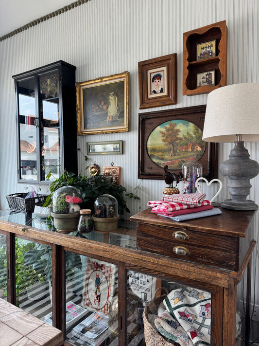 A traditionally decorated room with old paintings, gold and wood frames, and an antique table with assorted decor
