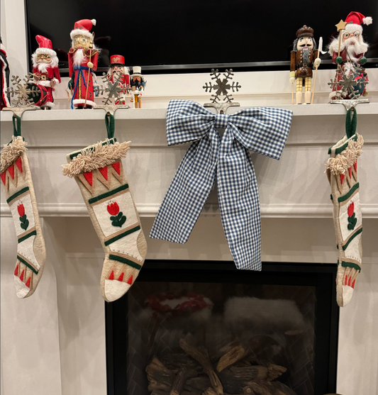 Blue gingham bow on a Christmas mantle decorated with stockings and festive holiday decor